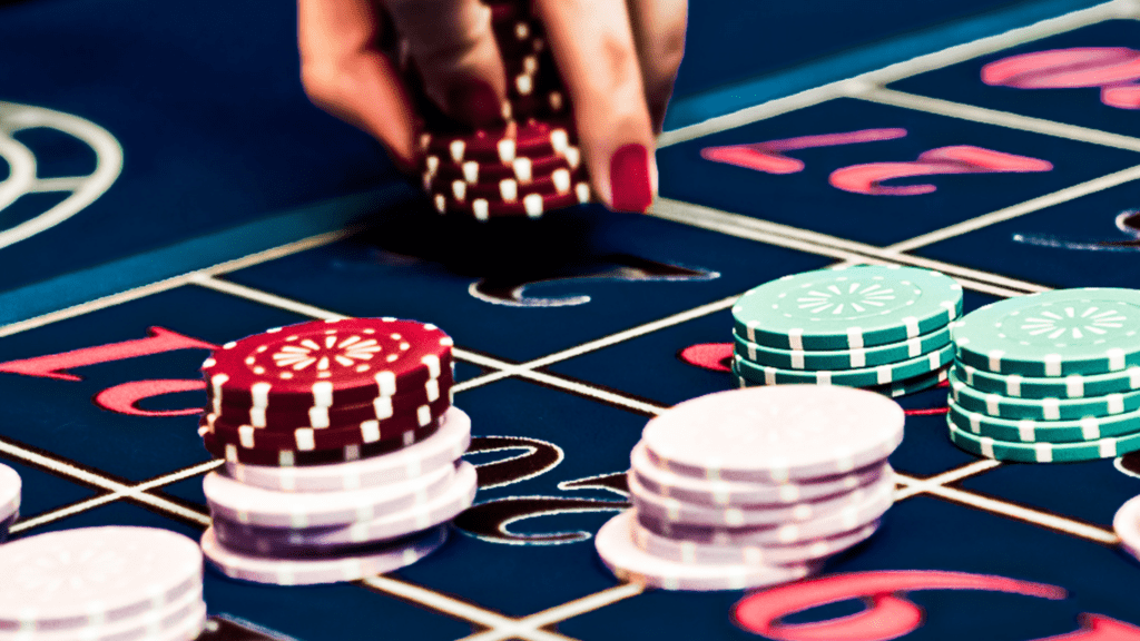 A hand is holding a stack of chips on a roulette table