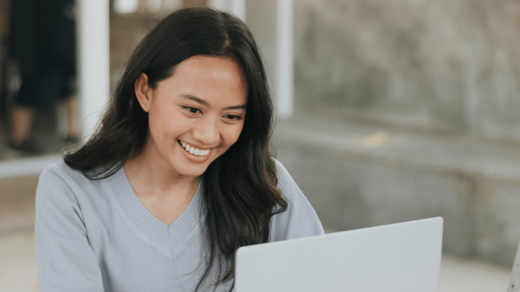 A smiling person working on a laptop