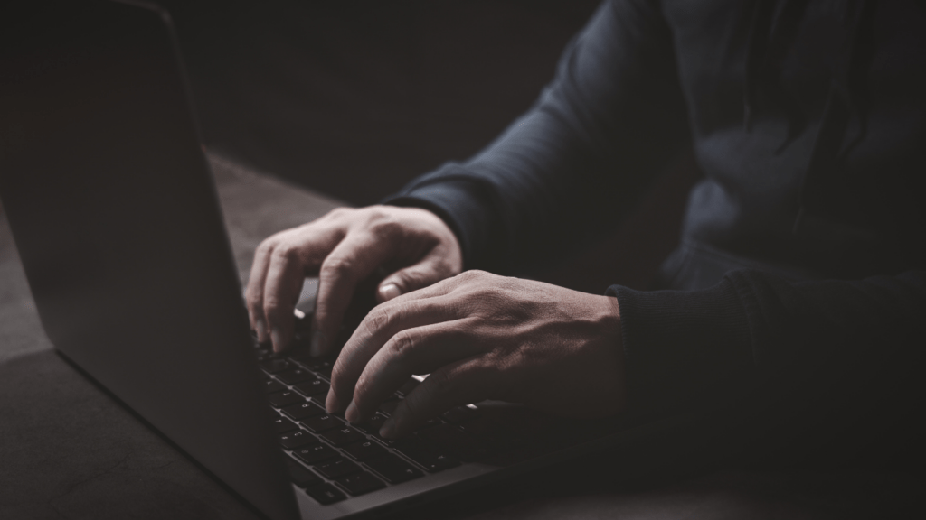 a person typing on a laptop computer in the dark