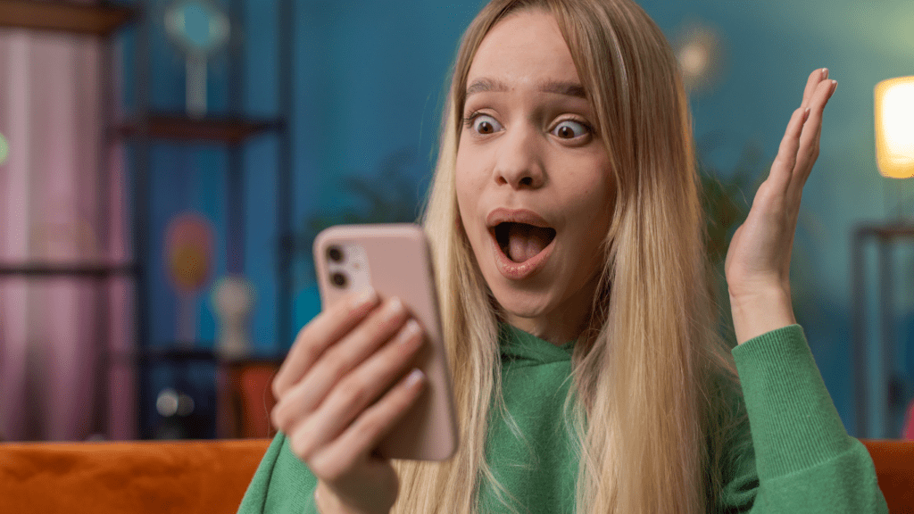 A surprised person looking at their phone while sitting on a couch