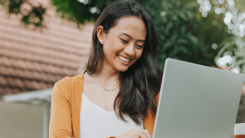 a person smiles while using a laptop computer