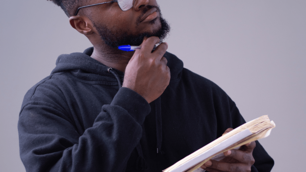 a person with glasses and a black shirt standing in front of a white wall