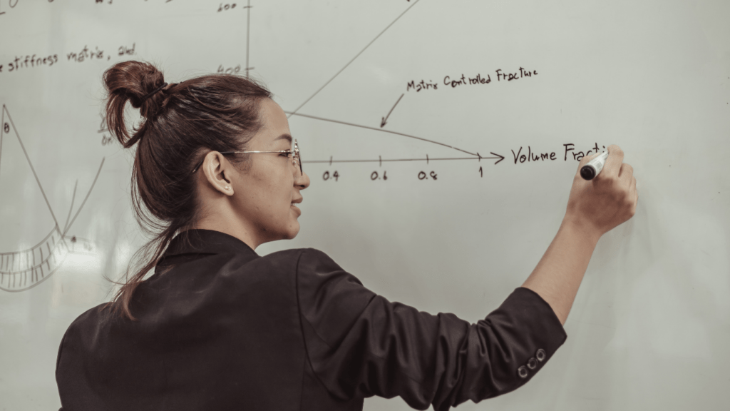 a person writing on a blackboard with formulas written on it