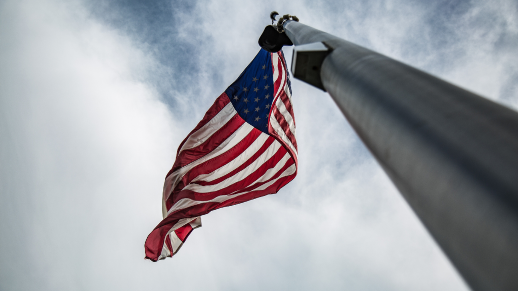 an american flag blowing in the wind against a blue sky